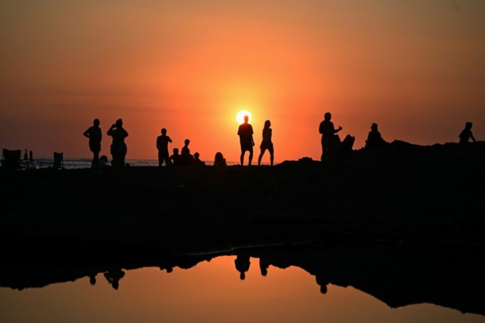 Turistas disfrutan del atardecer en la playa El Tunco, en La Libertad, El Salvador, el 13 de febrero de 2026. AFP