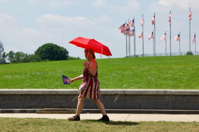 Una mujer camina por el National Mall de Washington bajo un paraguas para protegerse del sofocante calor el 3 de julio de 2026. AFP