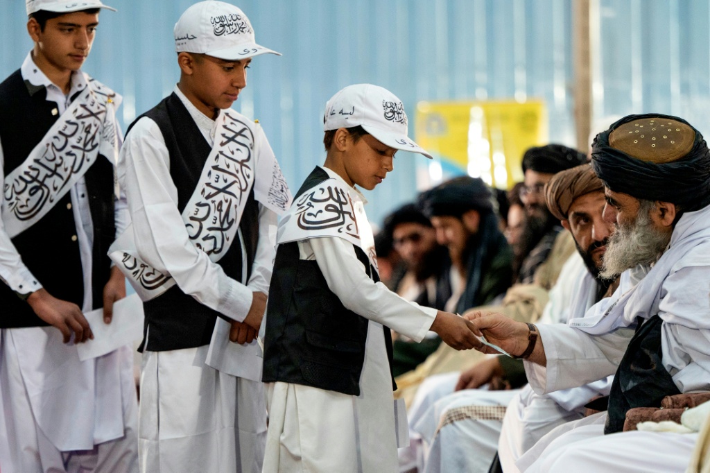Alumnos reciben dinero en efectivo del ministro de Educación de los talibanes, Habibulá Agha, en una ceremonia escolar en Kabul