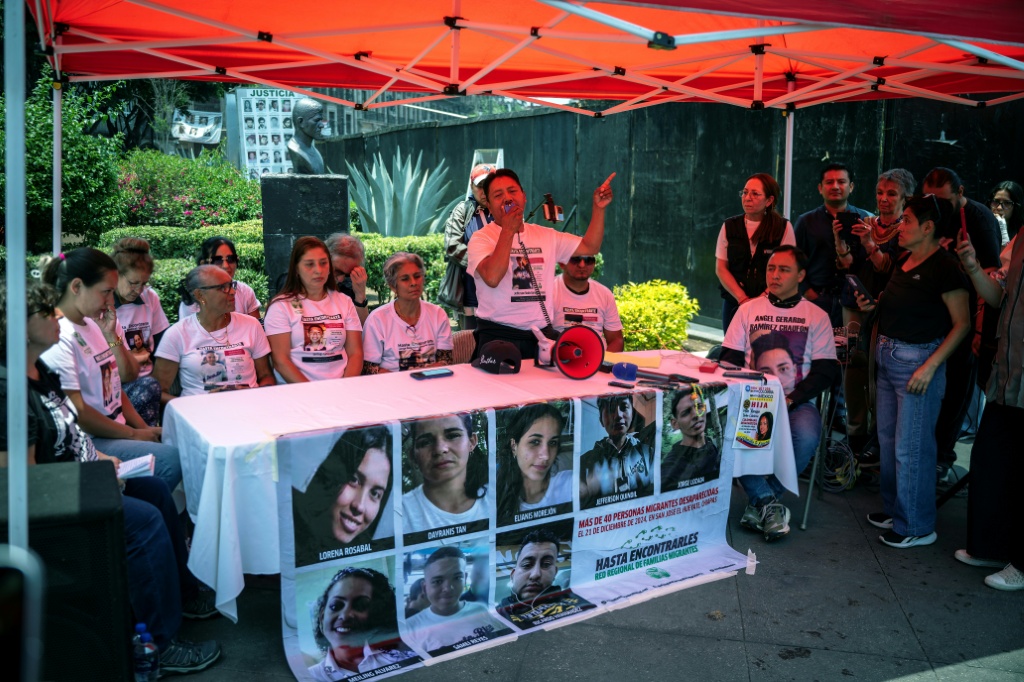 Participantes en un acto público con pancartas y fotografías de personas desaparecidas en México.